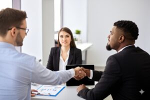 two people shaking hands while a third person (the mediator) observes with a calm, approving expression