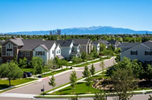 well-maintained residential neighborhood in denver with clean landscaping, tree-lined streets, and the city skyline in the background, representing a thriving hoa community